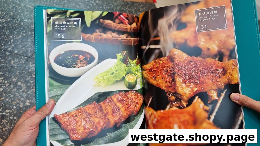 A close-up of a menu displaying charcoal-grilled pork belly and chicken wings with prices.