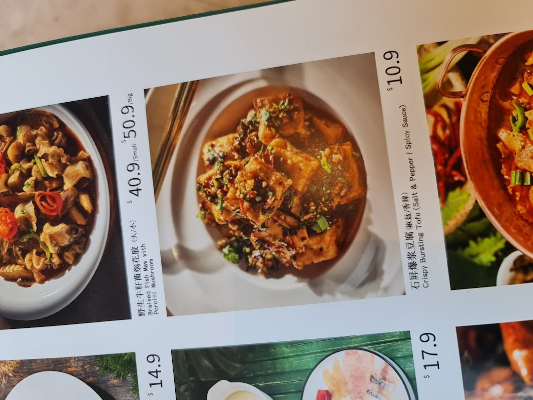 A close-up of YUN NANS restaurant menu, showcasing Braised Fish Maw and Crispy Bursting Tofu dishes with prices.